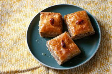 Doğu mutfağı, tatlılar, ev yapımı fırın, cevizli Türk baklavası ve yeşil tabakta turuncu sirk ve çay havlusu. Lezzetli tatlı.