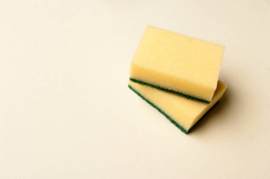 Açık arkaplanda iki sarı sünger. Uzayı metin için kopyala. Temizlik kavramı.