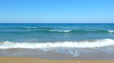Mavi denizin kıyısı, yumuşak dalgalar, beyaz köpük, berrak gökyüzü