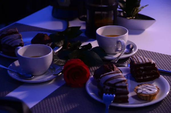 white cups of tea, cupcakes, cake, red rose on the table