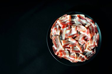 Domuz pastırması siyah arka planda dilimlenmiş. İspanyol geleneksel eti. Boşluğu kopyala