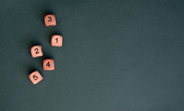 Koyu yeşil arka planda farklı numaralara sahip beş tahta zar, kaybet. Boşluğu kopyala.