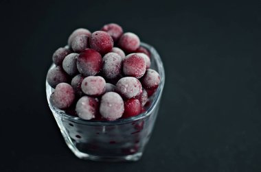 Donmuş kırmızı kirazlar siyah arkaplanda cama yakın, boşluğu kopyala