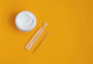Yüz kremi, serum, cam çubuk, sarı arka planda, yakın plan, kopyalama alanı