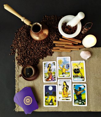 Tarot kartları ve fal bakımı, branda peçete arka planı, kahve fincanı ve kahve çekirdekleri.