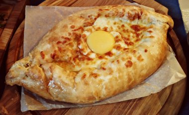 Geleneksel Ajarian yassı ekmeği - Khachapuri. Ahşap tahtada mozarella peynirli ve yumurtalı turta, yakın plan..