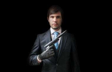 Hitman or murderer with pistol with silencer on black background. Low key photo. clipart