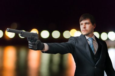 Agent or hitman is aiming with pistol with silencer at night. clipart