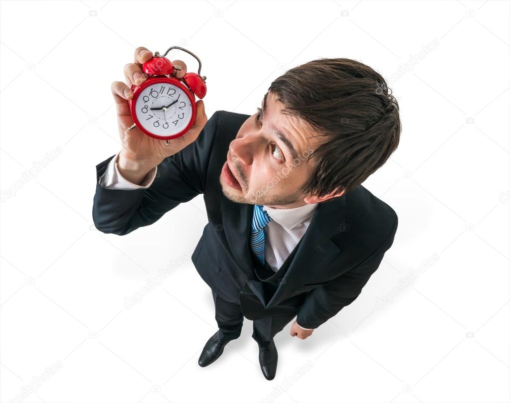 Deadline concept. Young stressed businessman is looking at clock and have to hurry. View from top. Isolated on white background.