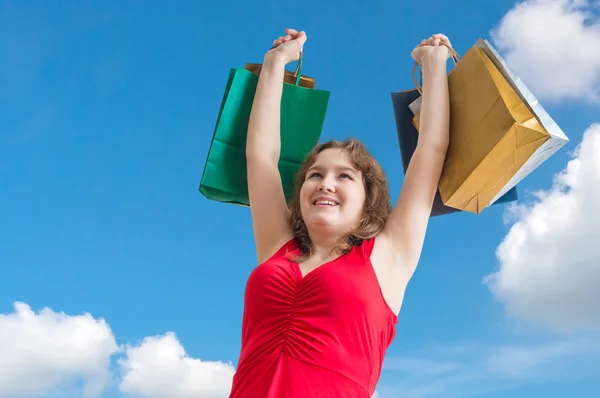 Молодая веселая леди держит сумки в руках против голубого неба . — стоковое фото
