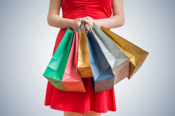 Концепция покупок. Женщина в красном платье держит много красочных мешков . — стоковое фото