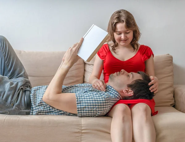 Młoda para są odpoczynku na kanapie i czytanie książek. — Zdjęcie stockowe