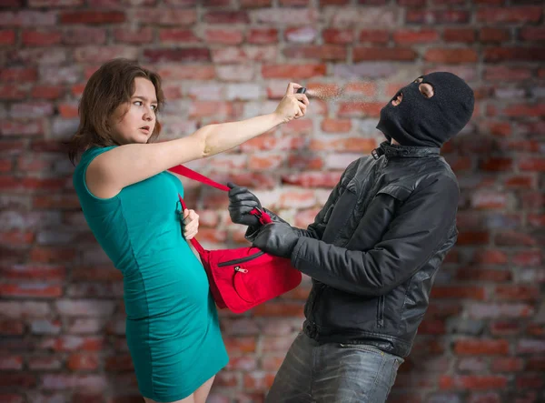 Zelfverdediging concept. Jonge vrouw is vechten met de dief en het gebruik van pepperspray. — Stockfoto