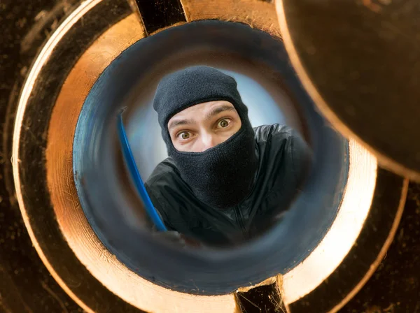 Zobrazit prostřednictvím pipehole. Zloděj nebo lupič maskovaný s kuklu za dveřmi. — Stock fotografie