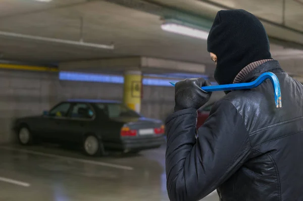 Zloděj s páčidlo se chystá ukrást auto z garáže. — Stock fotografie