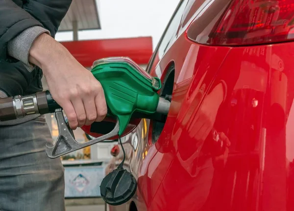 Człowiek jest pompowanie gazu w czerwony samochód w stacji paliw. — Zdjęcie stockowe