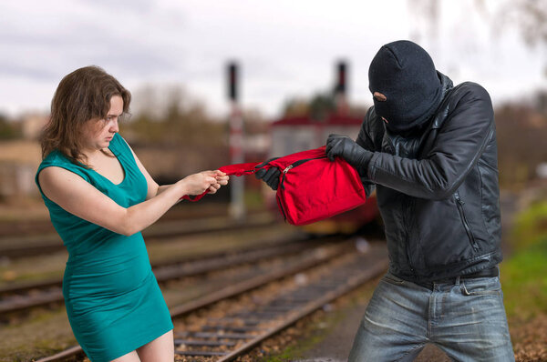 Thief is fighting with woman and stealing handbag.