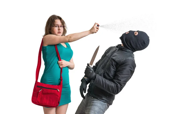 Jonge vrouw verdedigt met pepperspray tegen gewapende dief met mes. Geïsoleerd op witte achtergrond. — Stockfoto