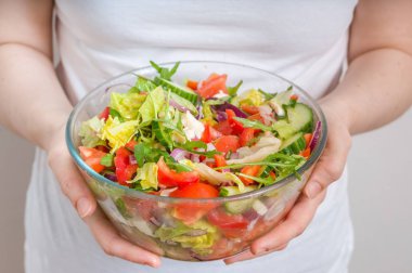 Kadın kase sebze salatası tam elinde tutan.
