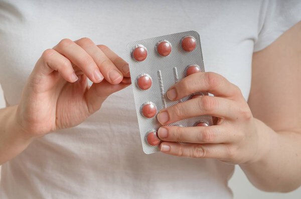 Young woman is taking pills from blister pack.