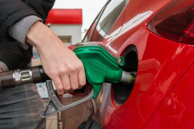 Adam kırmızı araçta yakıt istasyonu gaz pompalama.