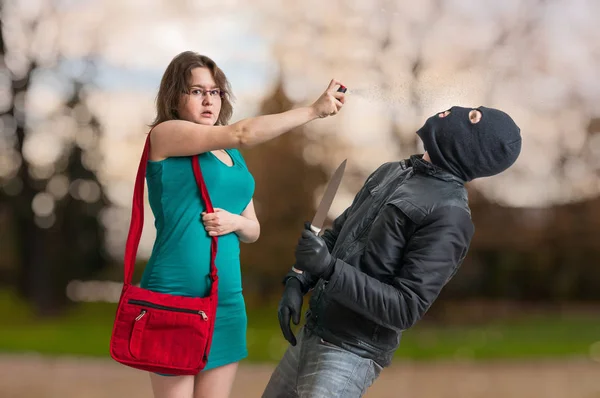 Jonge vrouw verdedigt met pepperspray tegen gewapende dief met mes. — Stockfoto