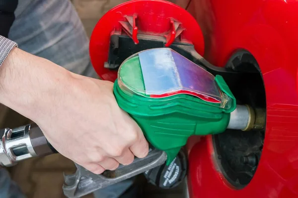 Mann pumpt Gas in rotes Auto in Tankstelle. — Stockfoto