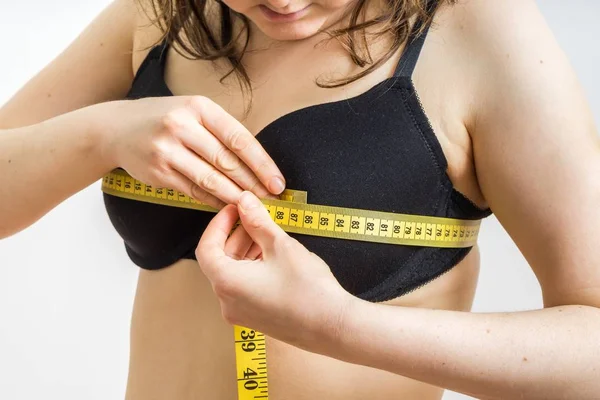 Donna sta misurando la sua dimensione del seno con un nastro . — Foto Stock