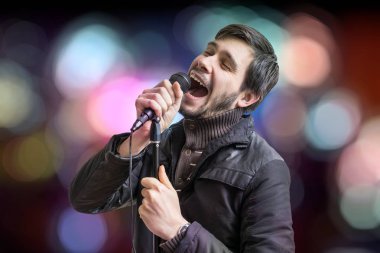 Karaoke kavramı. Genç adam mikrofon ve bulanık arka planda şarkı tutar.