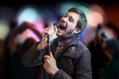 Genç adam bir şarkı söylerken ve insanlar kulüpte dans ediyor.