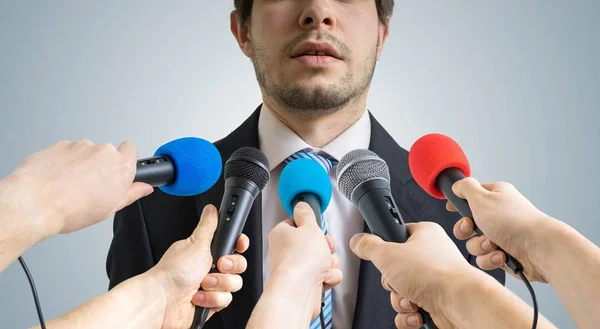 El político está hablando y dando una entrevista a los periodistas. Muchos micrófonos grabándolo delante . —  Fotos de Stock