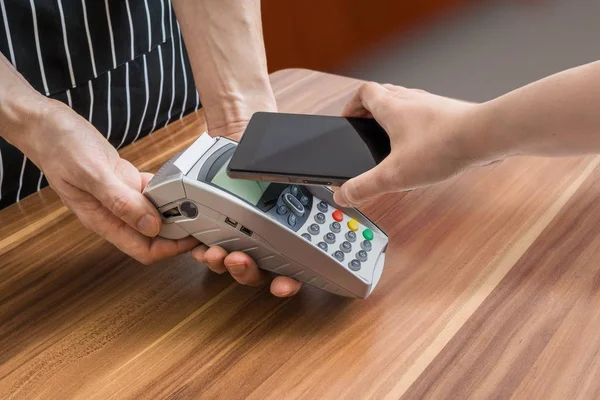 El cliente está pagando con teléfono inteligente en la tienda utilizando la tecnología NFC . — Foto de Stock