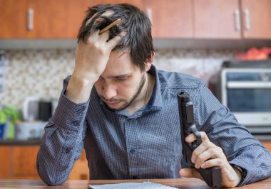 Üzgün adam elinde tabancayla. İntihar girişimi.