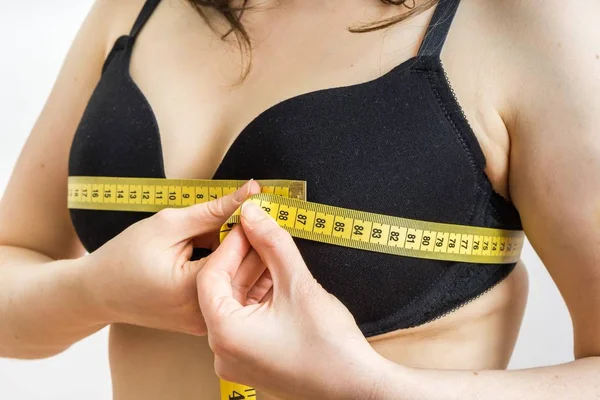 Donna sta misurando la sua dimensione del seno con un nastro . — Foto Stock