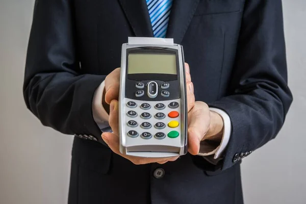 Businessman holds payment terminal in hands.