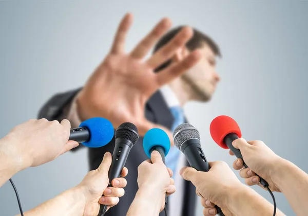 Many reporters are recording with microphones a politician who shows no comment gesture. — Stock Photo, Image