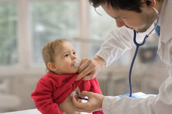 Врач-педиатр осматривает ребенка стетоскопом . — стоковое фото