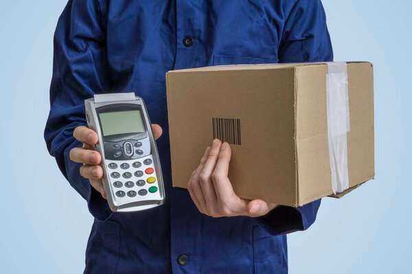 Package delivery concept. Man holds cardboard box and payment terminal in hands.