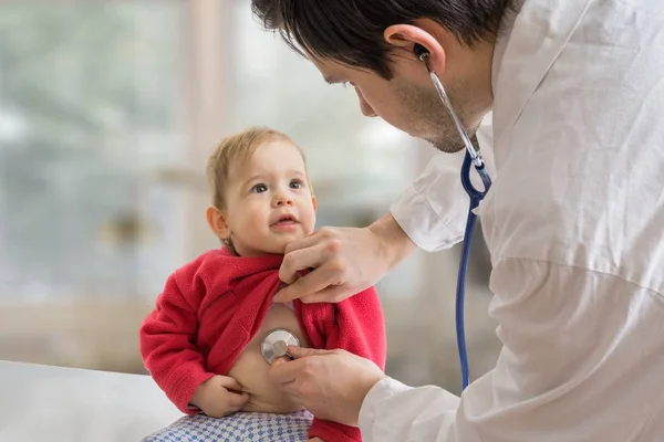 Médico pediatra está examinando a niño enfermo con estetoscopio . —  Fotos de Stock