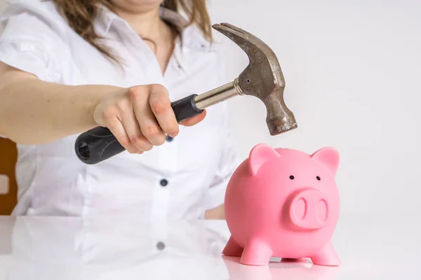 Mujer está rompiendo cerdito banco de dinero con martillo para tomar sus ahorros . —  Fotos de Stock