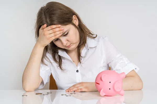 Jonge vrouw is de berekening van haar spaargeld in geld piggy bank. — Stockfoto