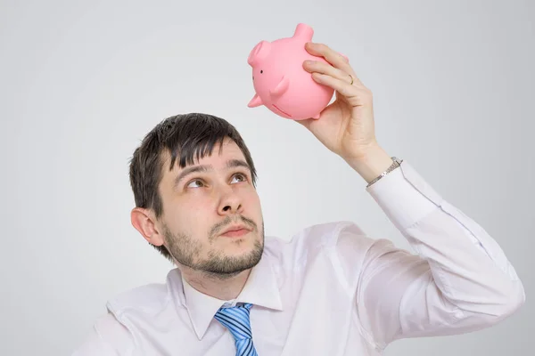 Junger Mann schaut in leeres Sparschwein. — Stockfoto