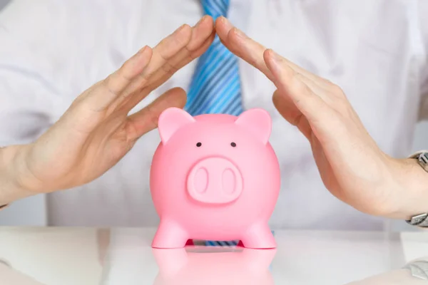 Verzekering en besparingen bescherming concept. Man is die betrekking hebben op geld piggy bank met handen. — Stockfoto