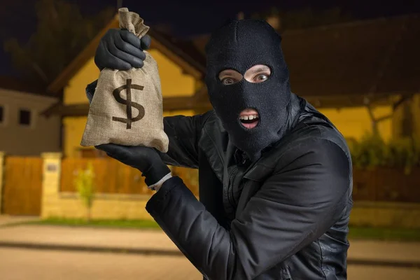 Ladrão feliz ou ladrão está mostrando saco roubado cheio de dinheiro à noite . — Fotografia de Stock