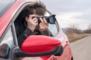 Paparazzi arabadan fotoğraf makinesi ile fotoğraf alıyor.