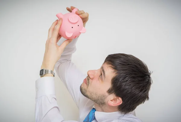 Jonge zakenman is op zoek in lege piggy geld bank. — Stockfoto