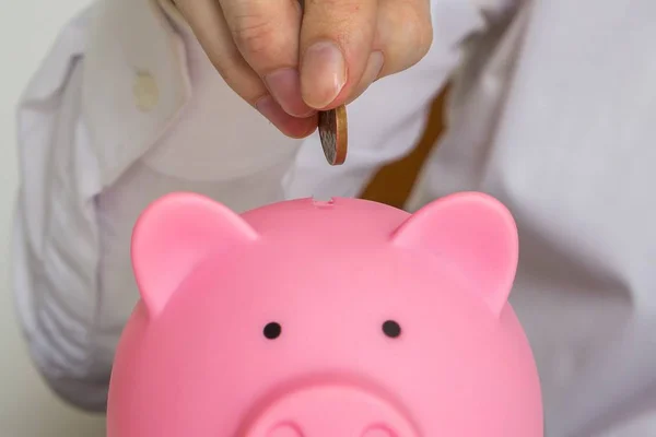 Man is aanbrengend piggy geld bank munt. — Stockfoto