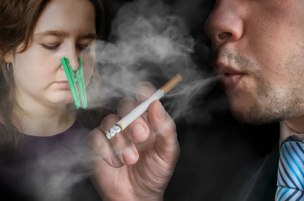 Concepto pasivo de fumar. El hombre egoísta está fumando un cigarrillo. Mujer no puede respirar y tiene clavija en la nariz . —  Fotos de Stock