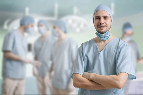 Udane chirurg się uśmiecha. Sporo lekarzy w tle. — Zdjęcie stockowe