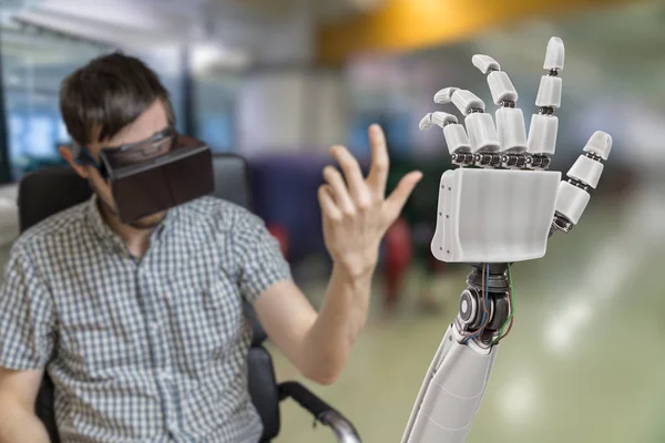 Νεαρός άνδρας είναι ο έλεγχος ρομποτικό χέρι με σετ κεφαλής εικονικής πραγματικότητας. — Φωτογραφία Αρχείου